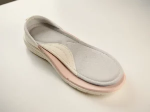 Orthopedische inlegzolen in een open diabetische schoen op een wit klinisch oppervlak, zachte natuurlijke belichting.