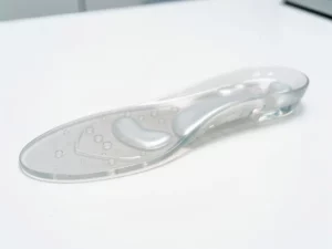 Transparante gel inlegzool op wit klinisch oppervlak, met zichtbare luchtzakjes onder de gewelfondersteuning.