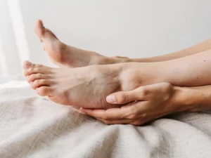 Koude bleke voeten op linnen, één voet omsloten door warme handen, zachte natuurlijke belichting, medisch empathische sfeer.